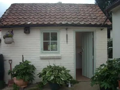 Photo of the outside of our parlor showing a small white bricked traditional english house with flowers